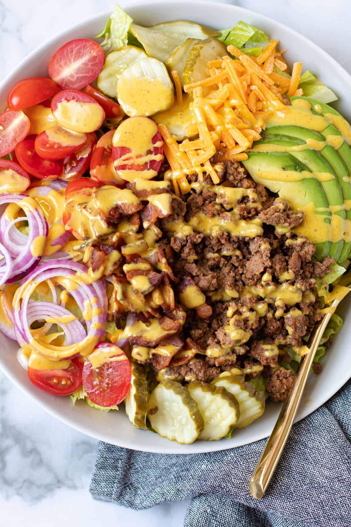 ground beef tomato and avocado in white bowl with mustard dressing