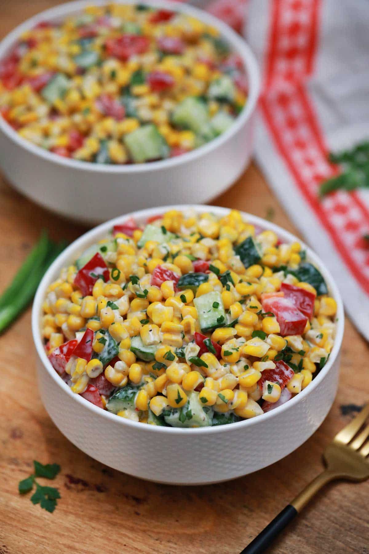 two white bowls of corn salad with peppers on table