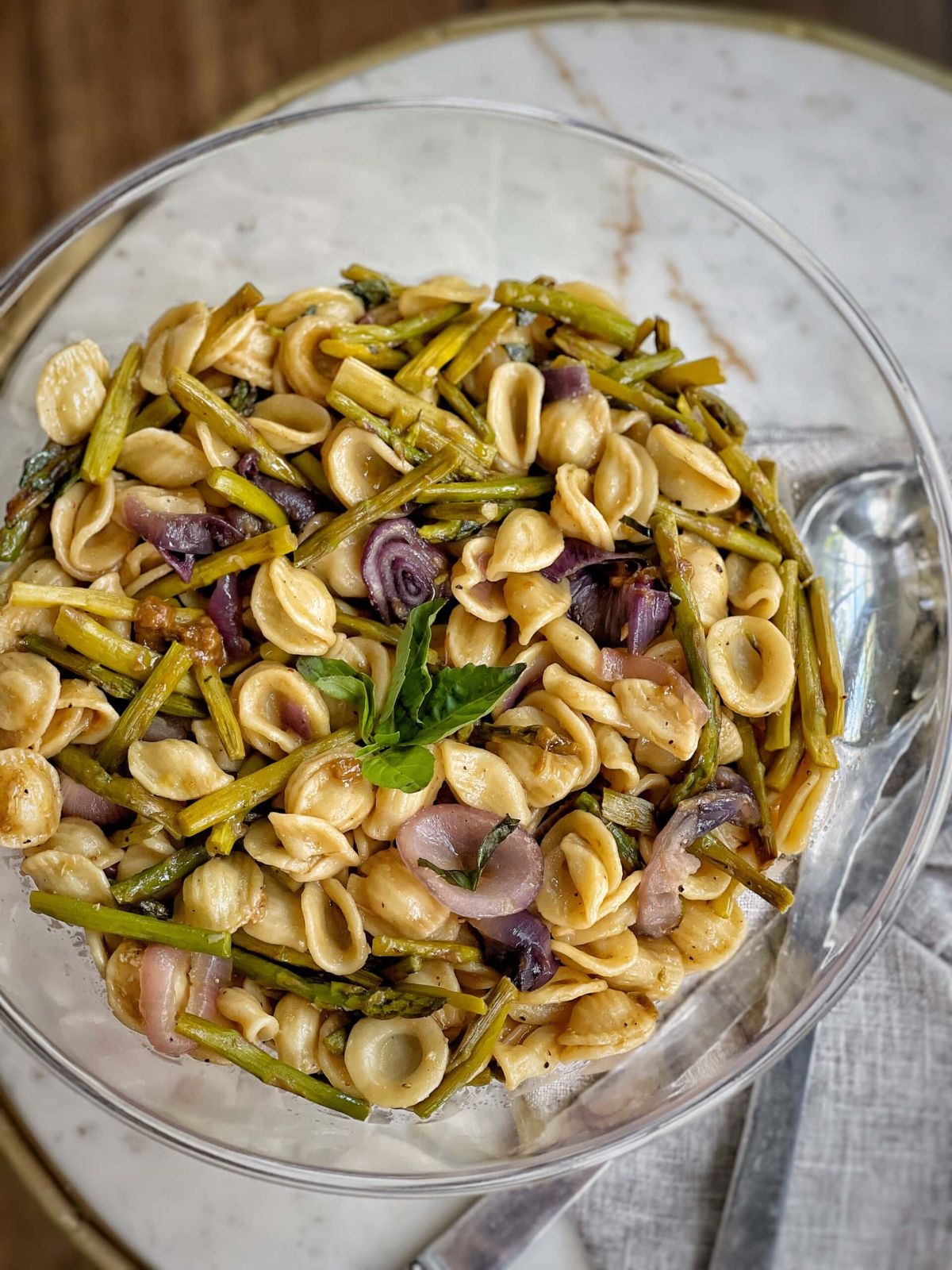 pasta salad in glass bowl with asparagus pieces