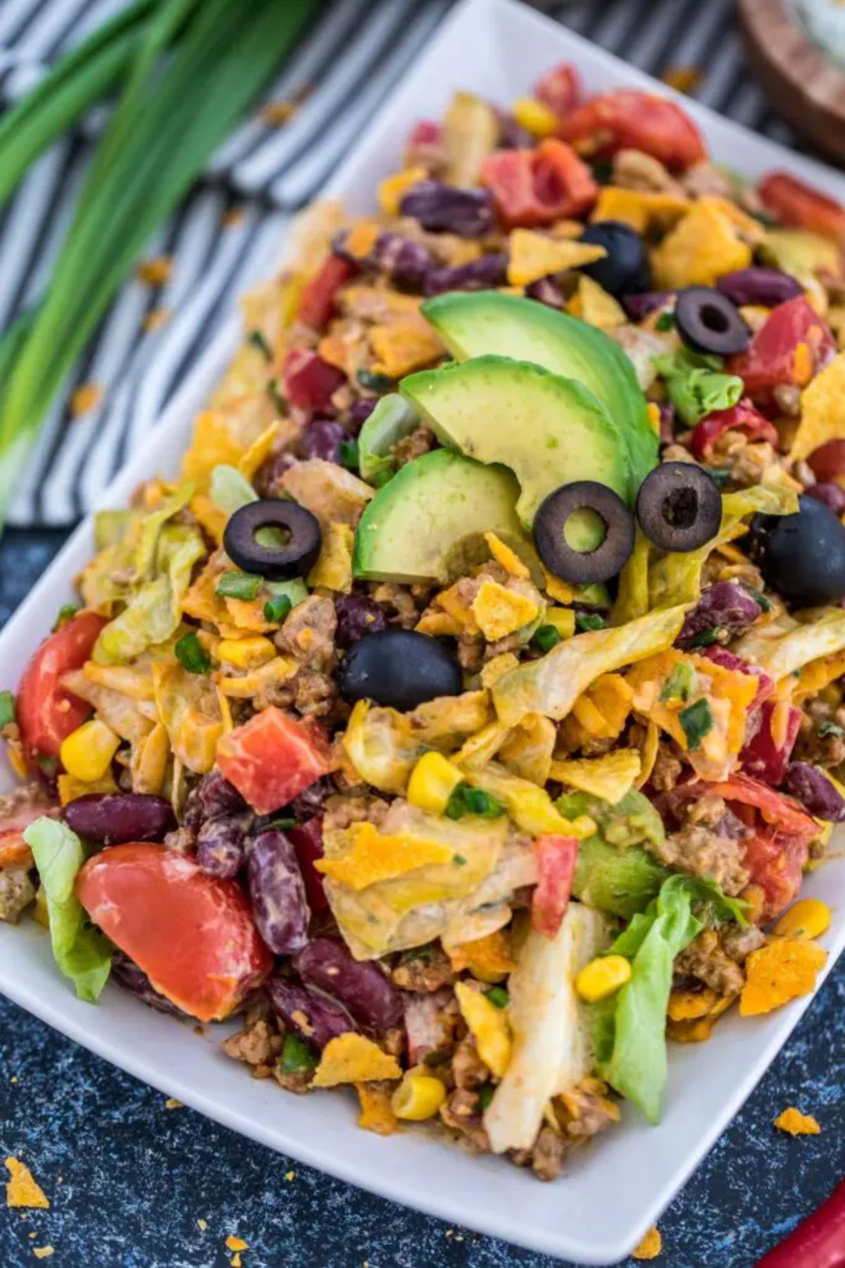 taco salad with avocado slices on white platter