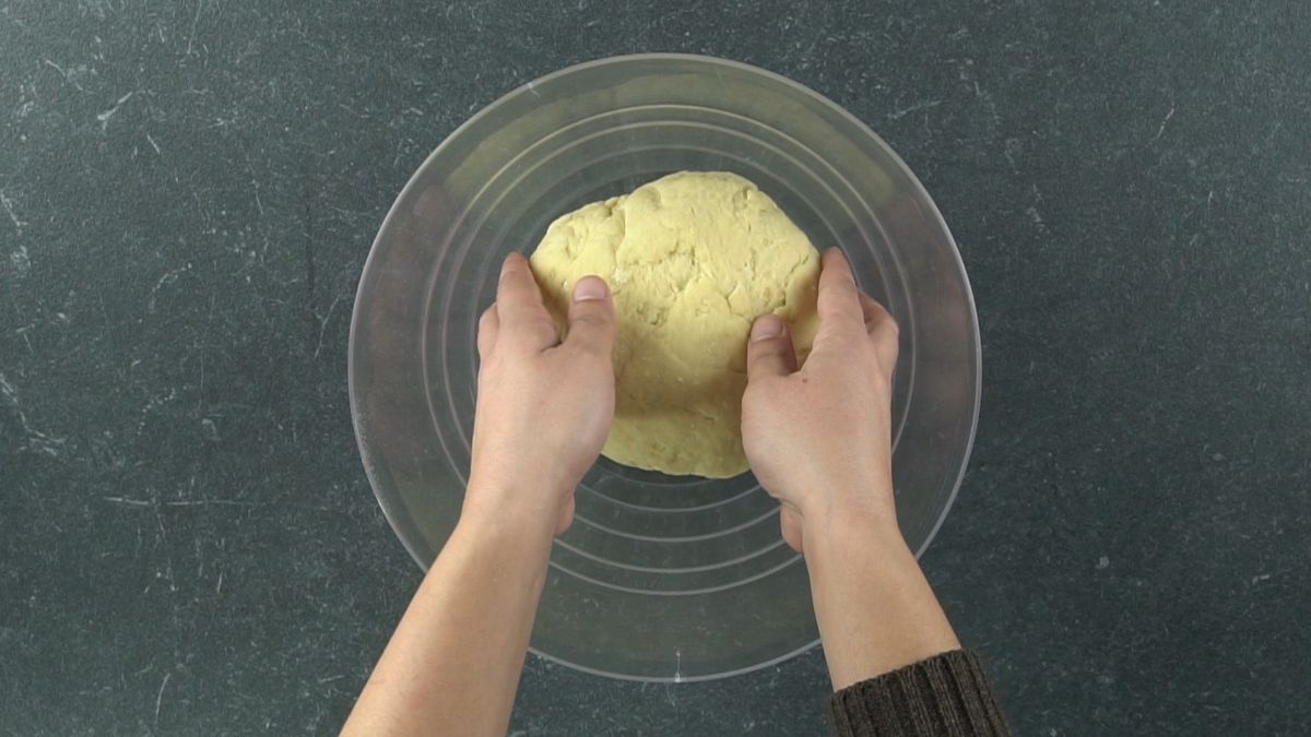 hands putting dough ball in glass bowl
