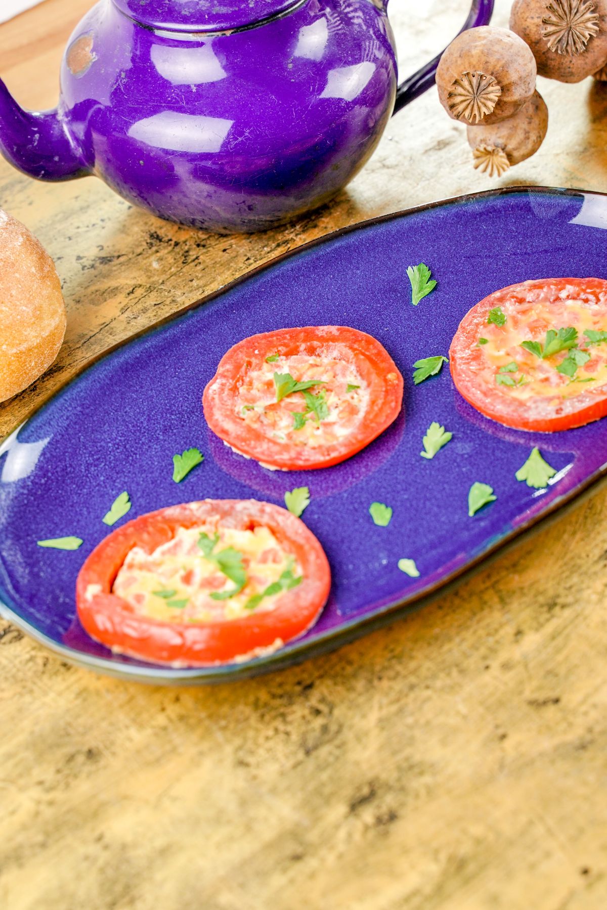 tomato egg rings on purple oval plate sitting on wood by purple tea kettle