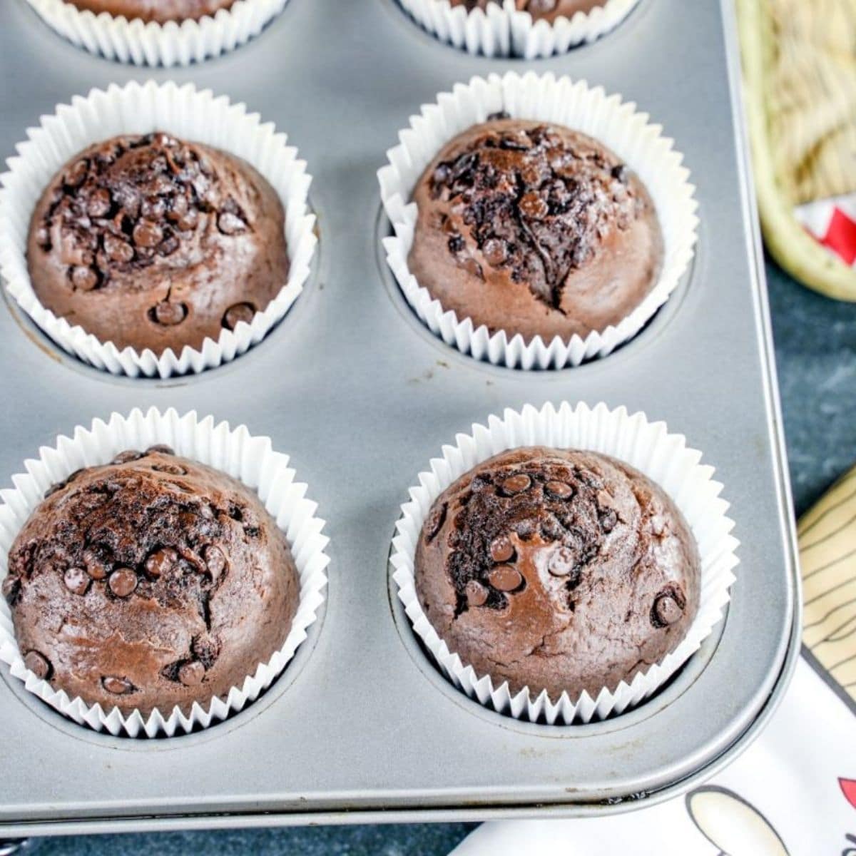 muffin tin with white liners filled with chocolate muffins