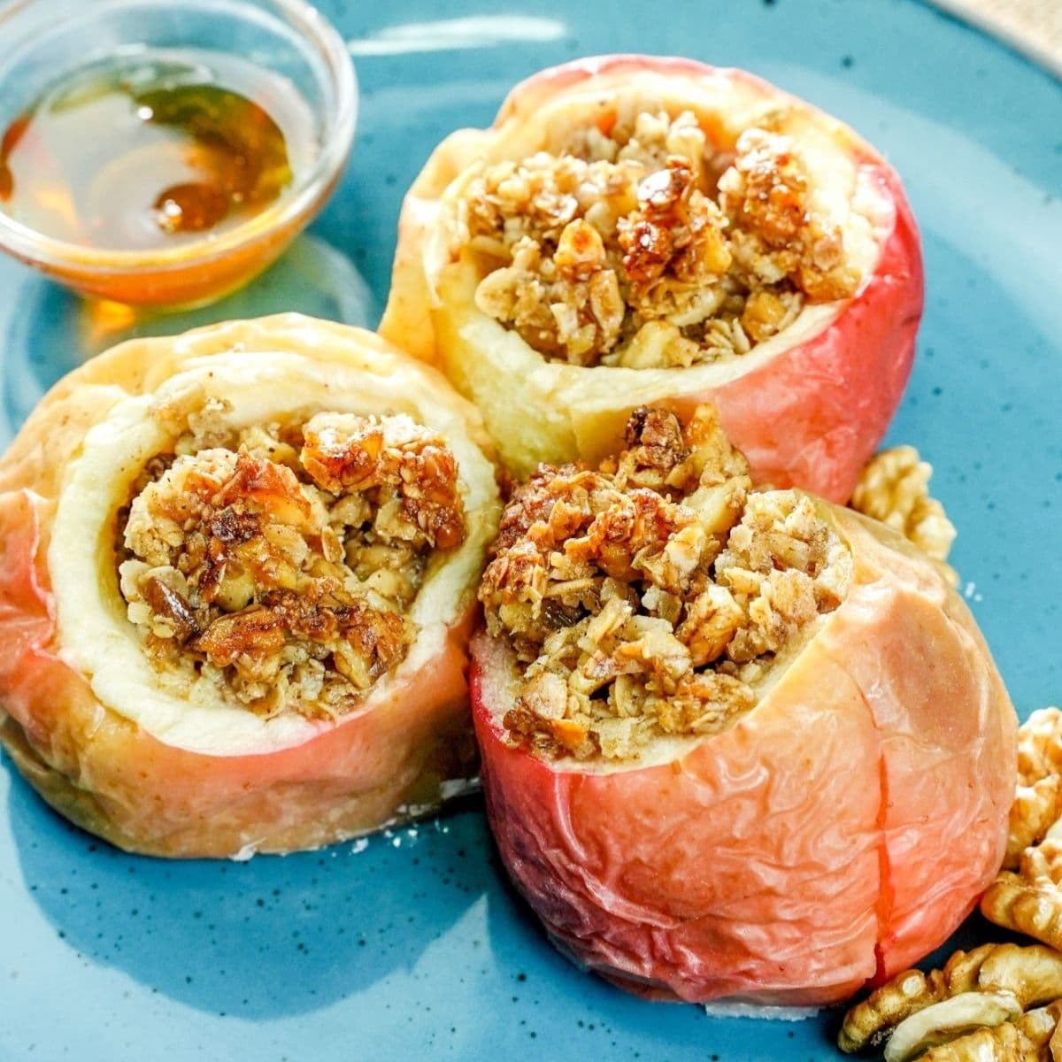 three oatmeal baked stuffed appls on teal plate with spoon