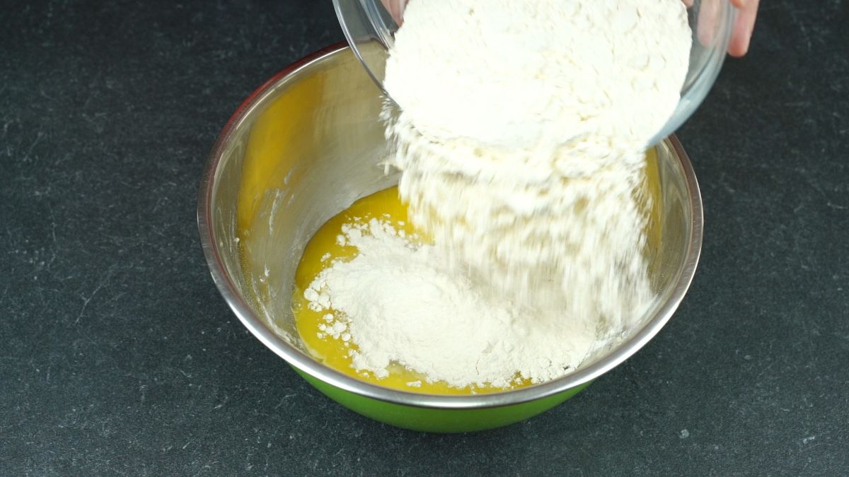 flour being poured into stainless steel bowl
