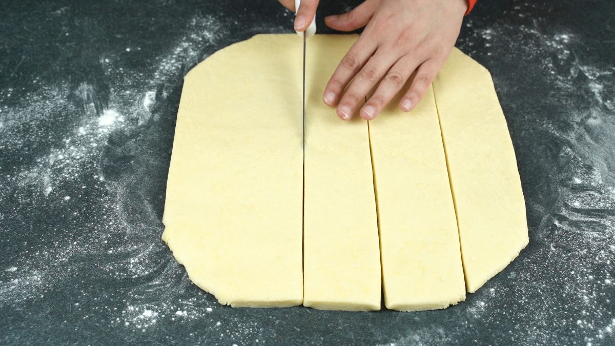 hand cutting dough on grey counter