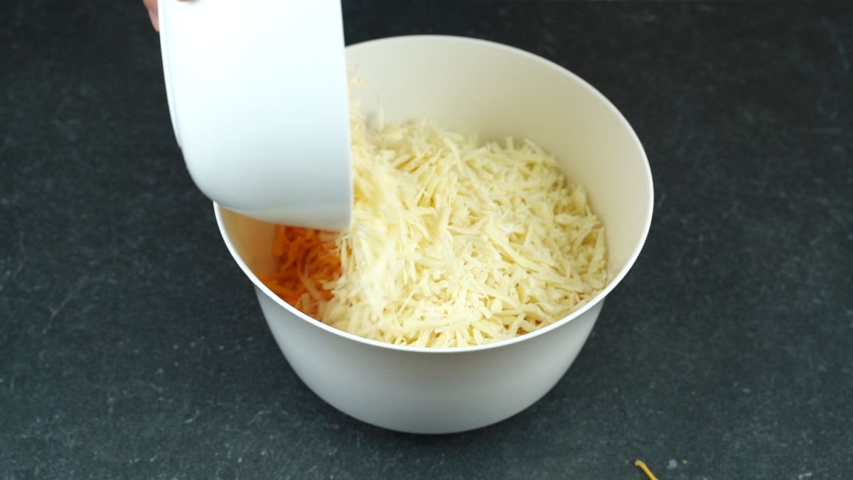 hand holding bowl of cheese being poured into white bowl