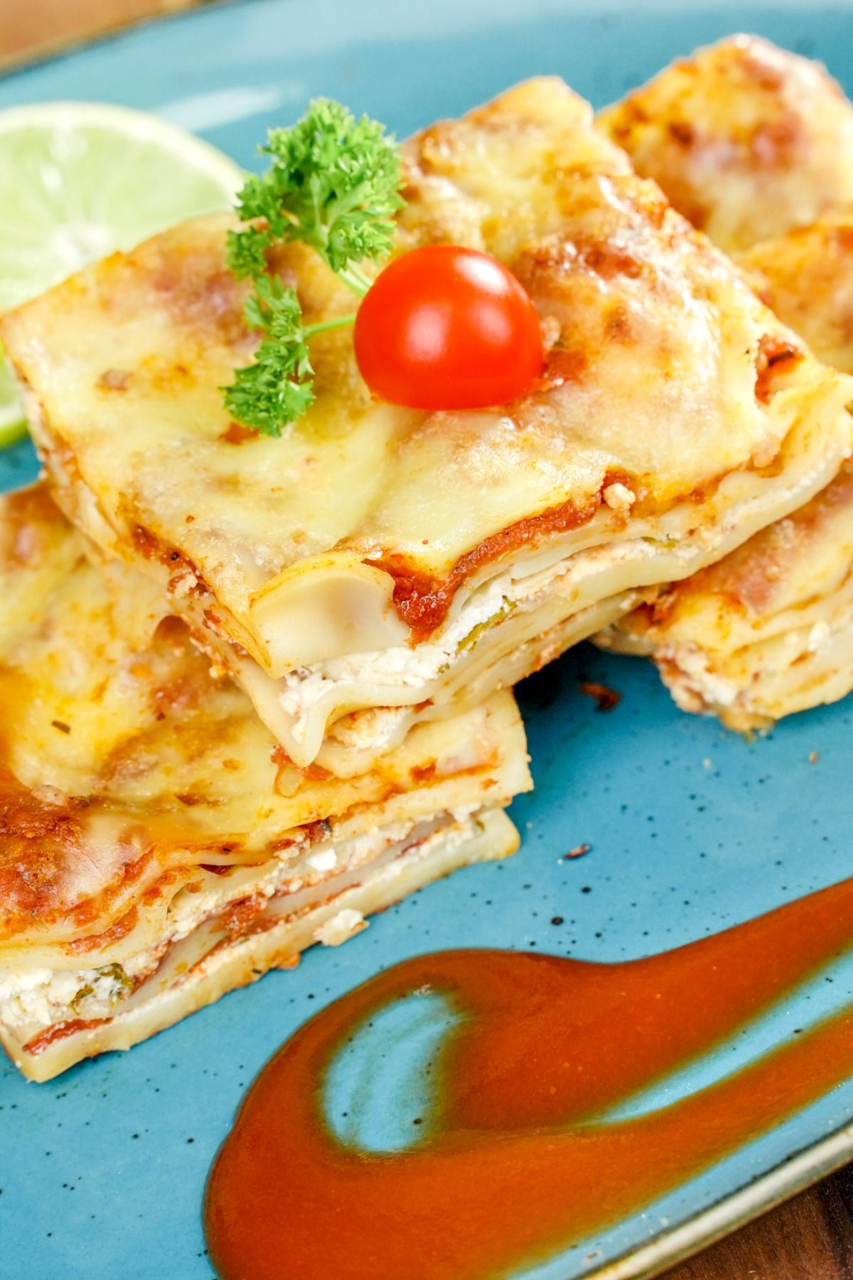 lasagna slices on teal plate with pasta sauce