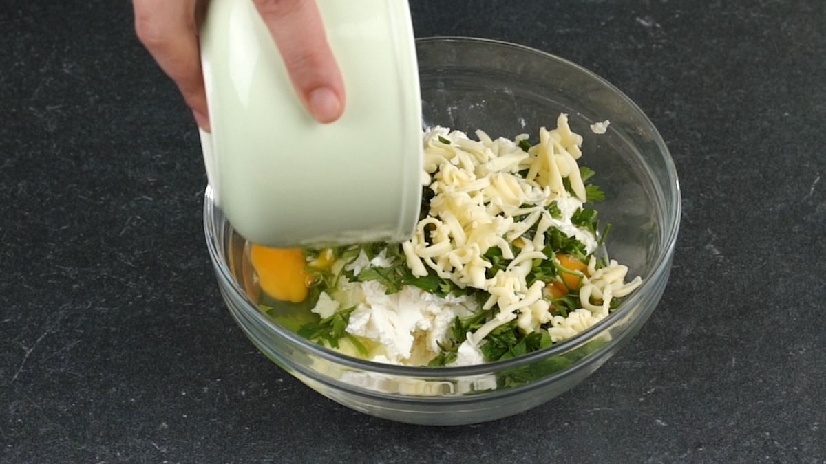bowl of cheese and herbs with egg being added