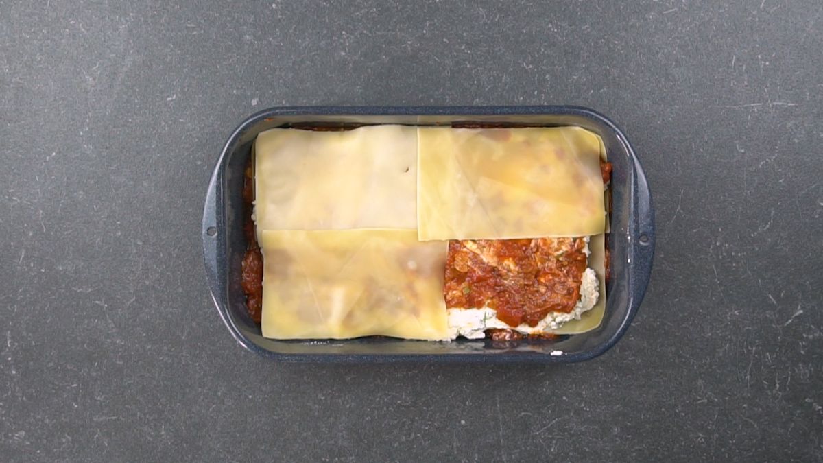 noodles on top of cheese and sauce in baking dish