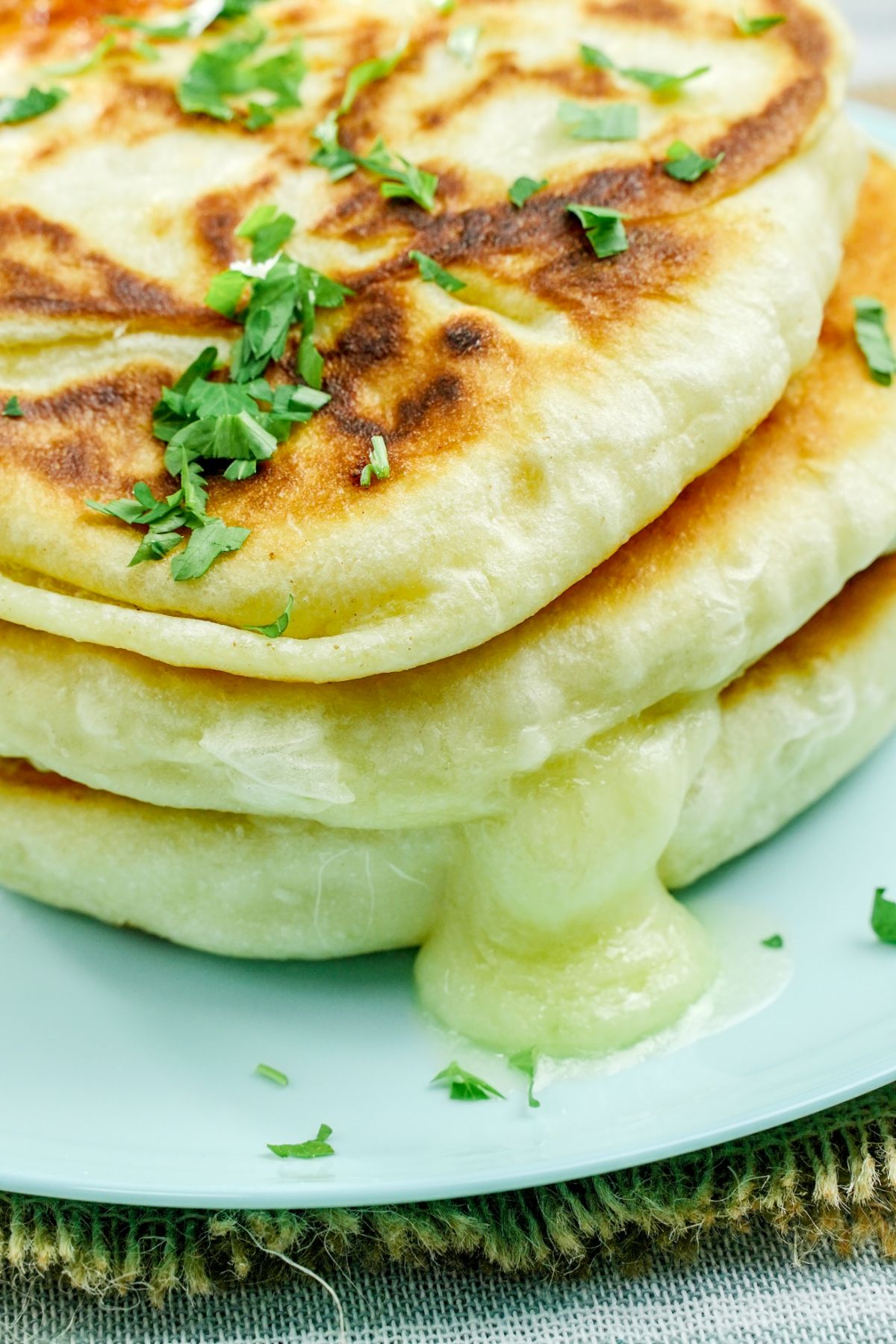 tall stack of piroshki with cheese melting out side on light blue plate
