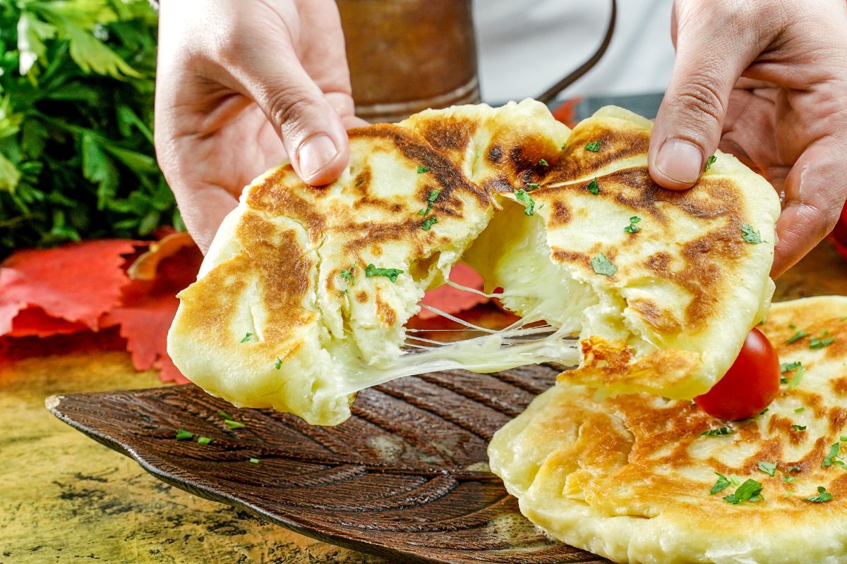 hand pulling apart bread with cheese filling