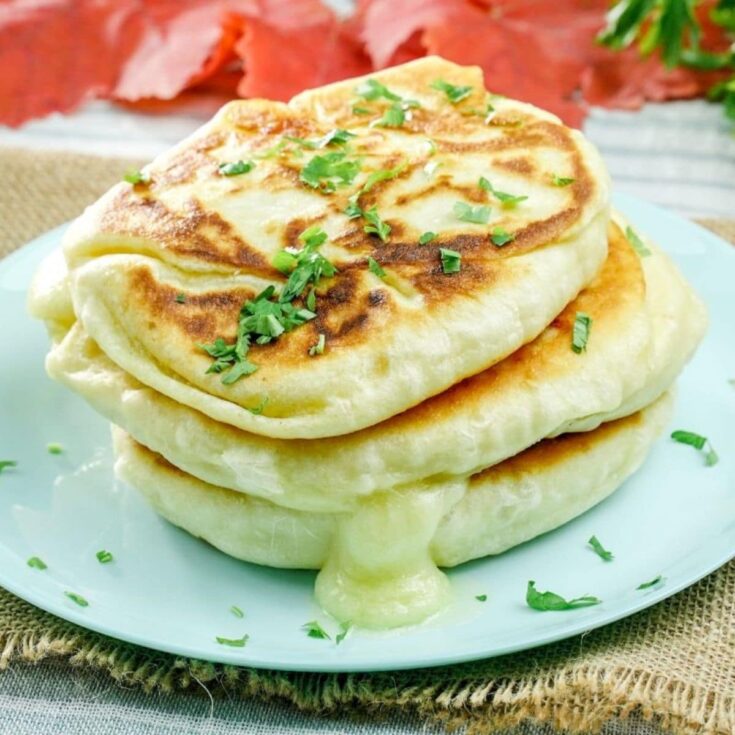 piroshki stacked on blue plate with cheese melting