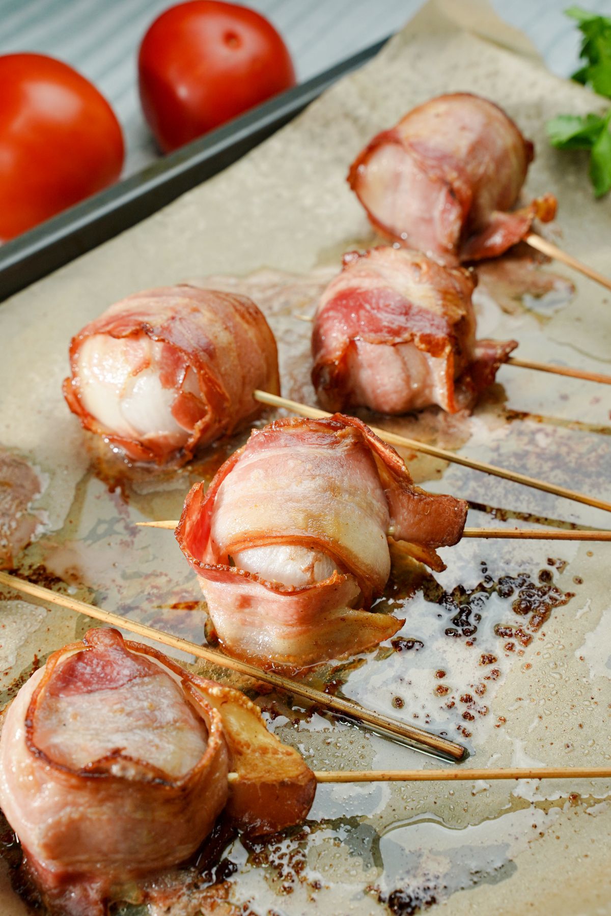 bacon meatball skewers on parchment paper on baking sheet