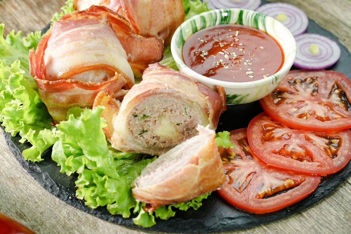 meatball cut in half on black plate with lettuce and tomato slices