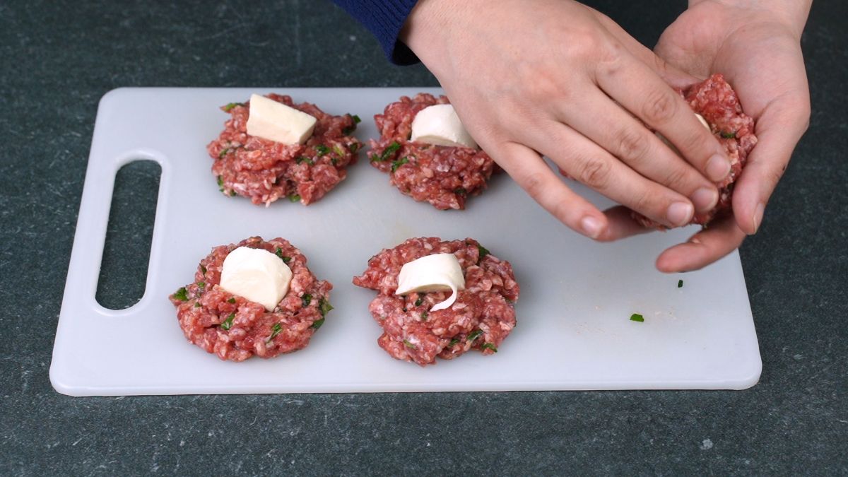 burger patties on cutting board with cheese in them