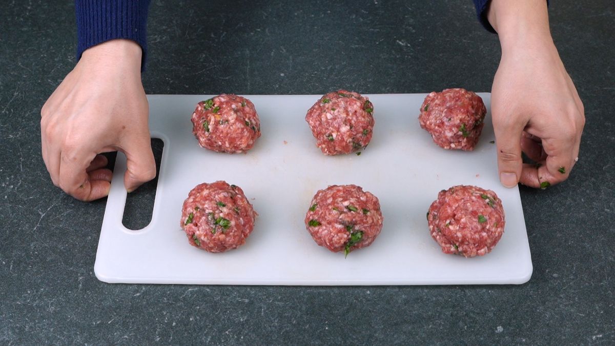 white cutting board with meatballs