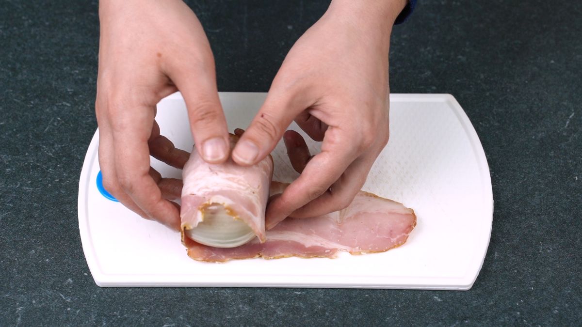 hand rolling meatball in bacon