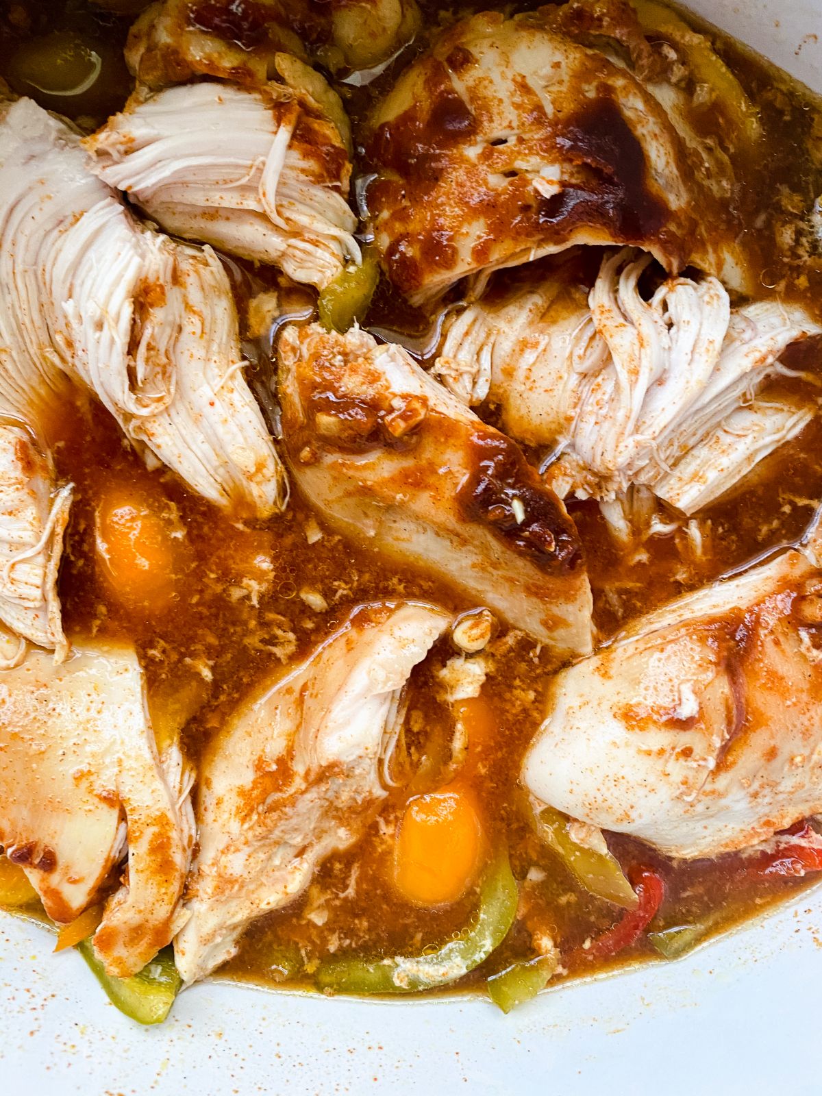 chicken in slow cooker with liquid being shredded