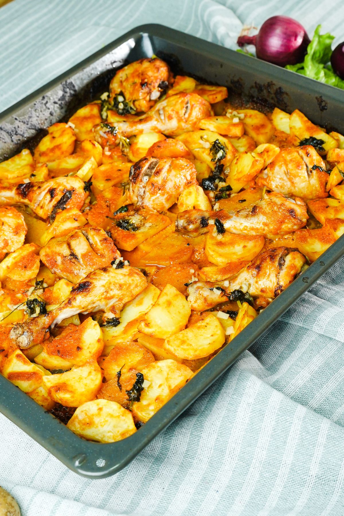 baking sheet of roasted chicken and potatoes laying on striped napkin