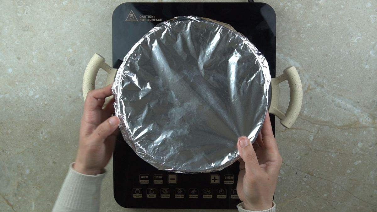 hand covering top of cake with foil