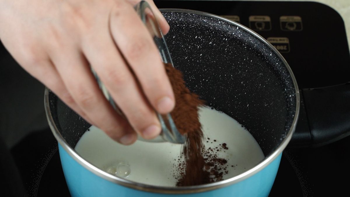 hand pouring cocoa into pan