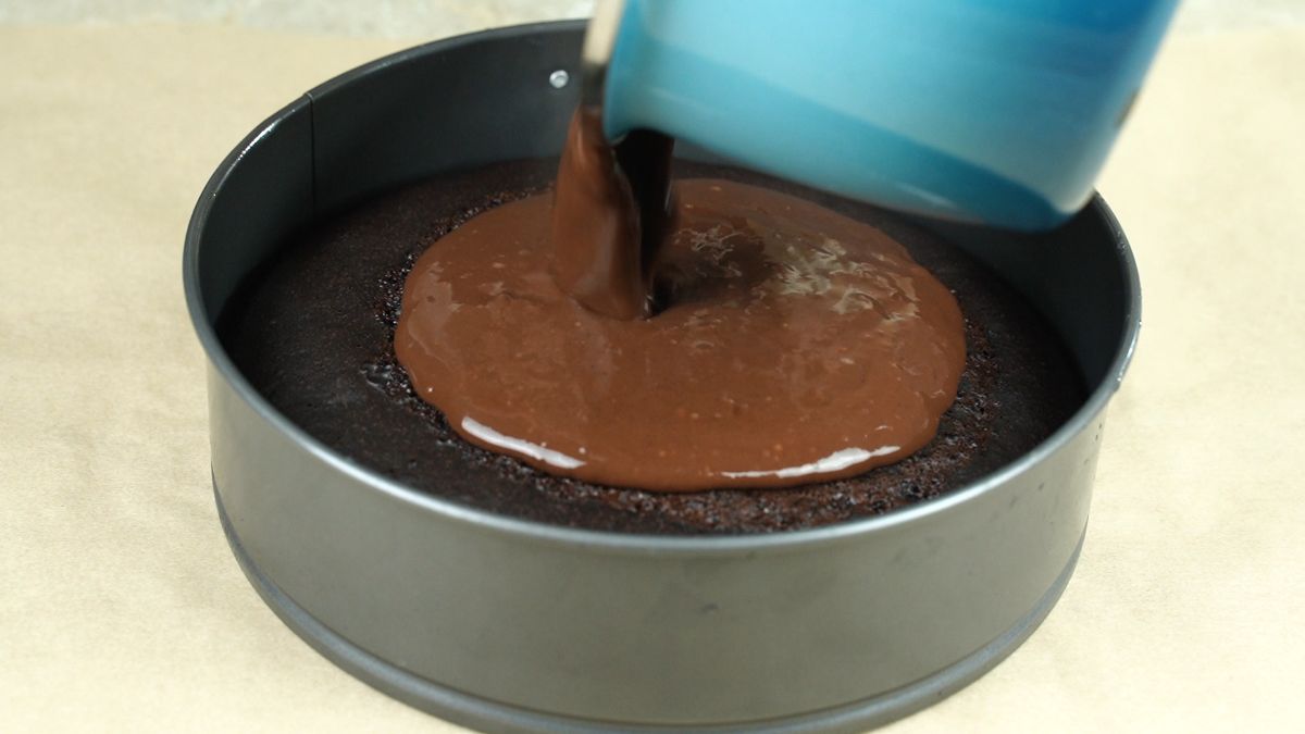 blue pan of ganache pouring over top of cake