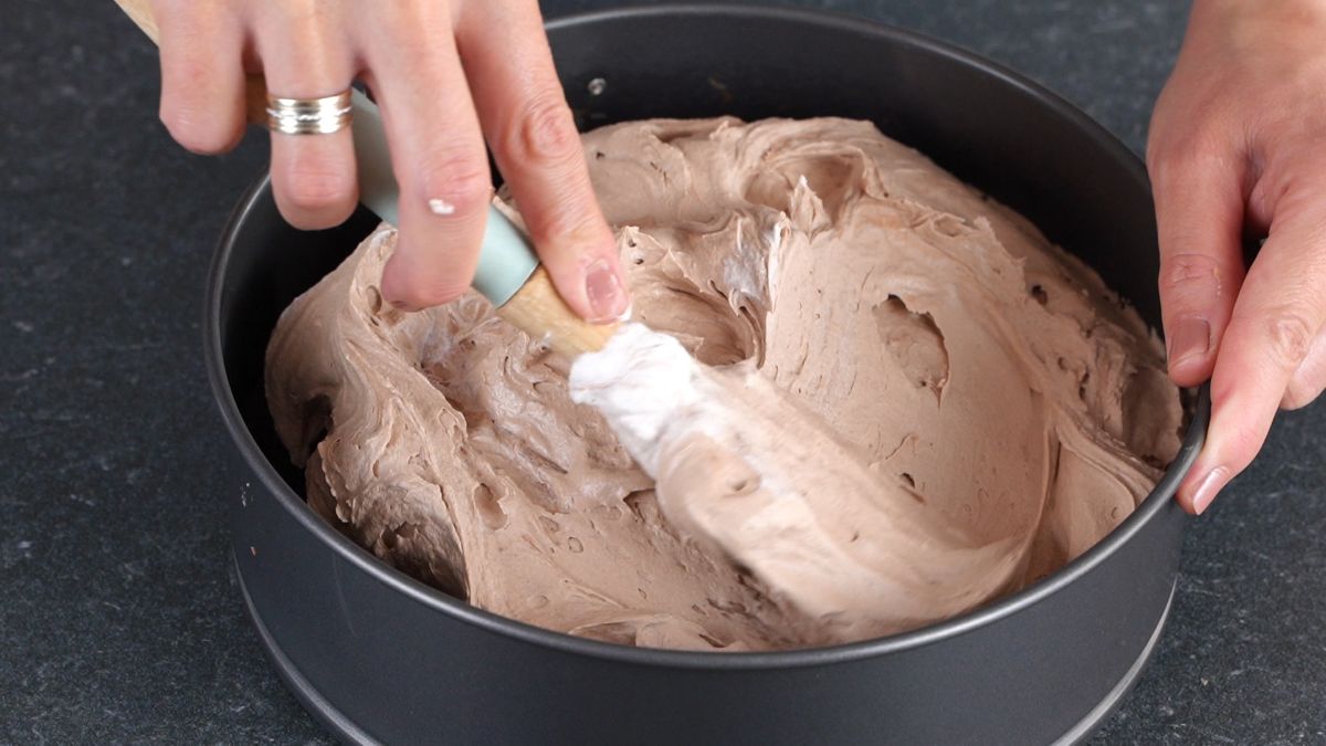 spatual spreading chocolate cream cheese into springform pan