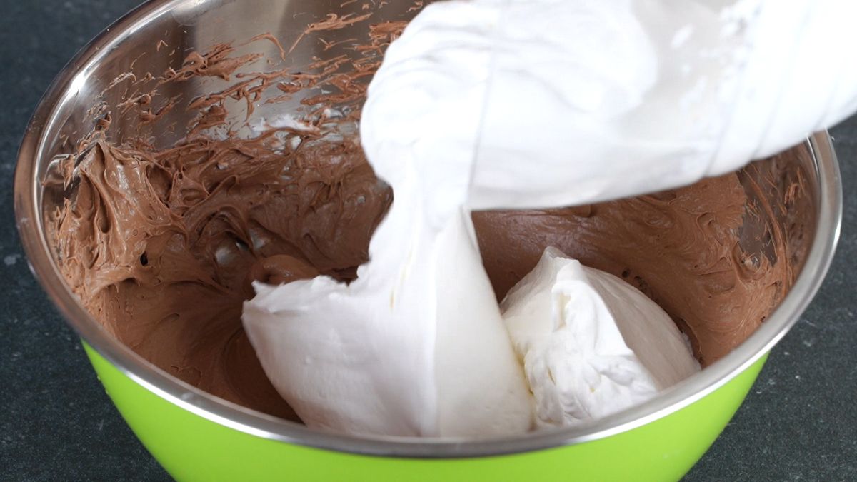 whipped cream being poured into bowl with chocolate