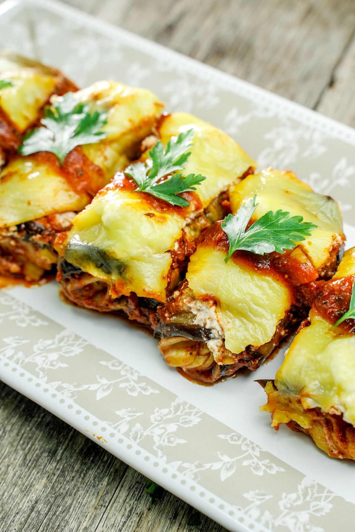eggplant rollups on white platter on wood table
