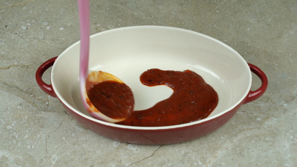 sauce being spread into baking dish