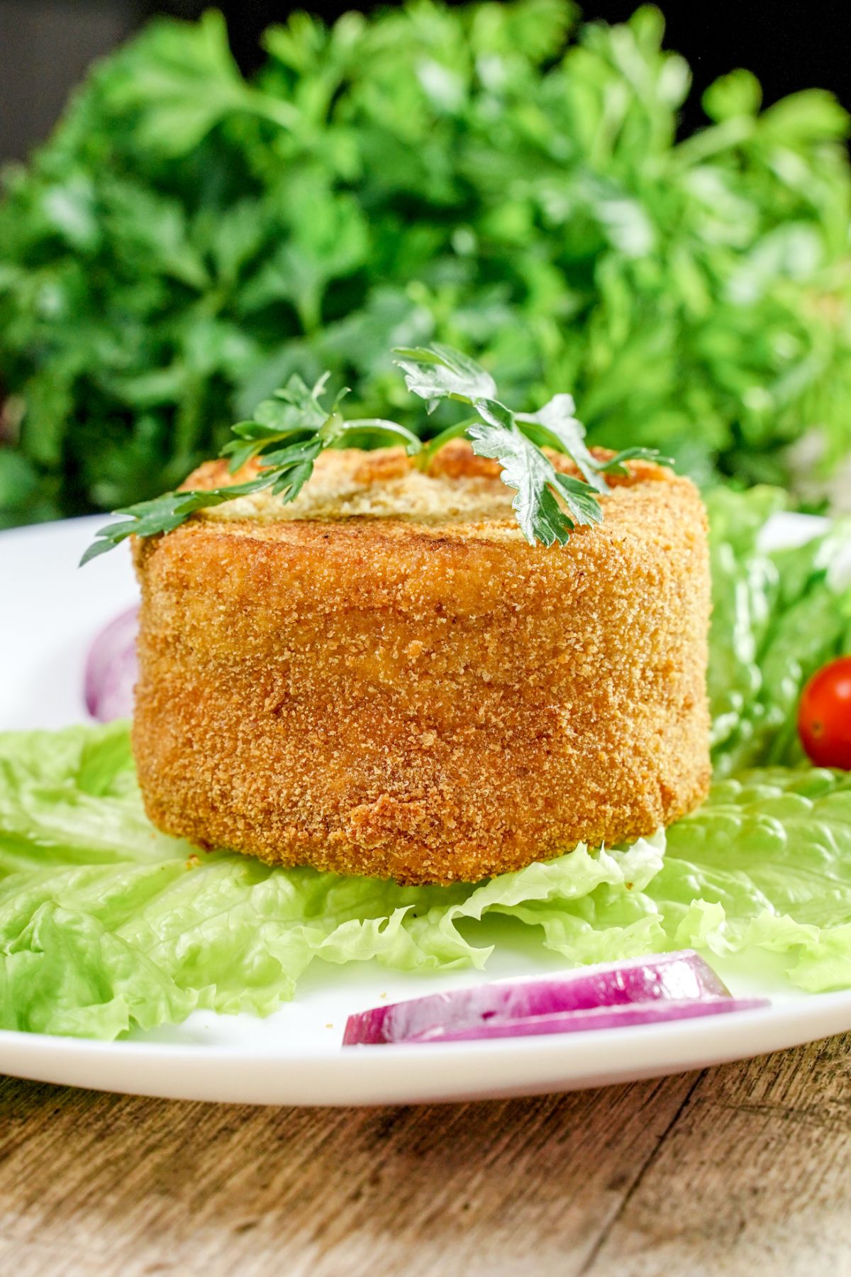 fried ham and cheese cutlet on plate with lettuce leave and red onoiin