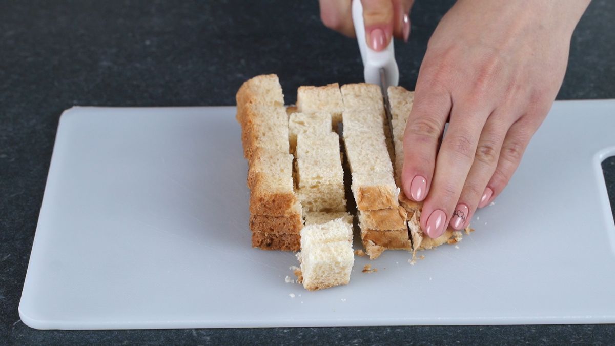 hand using white knife to slice bread