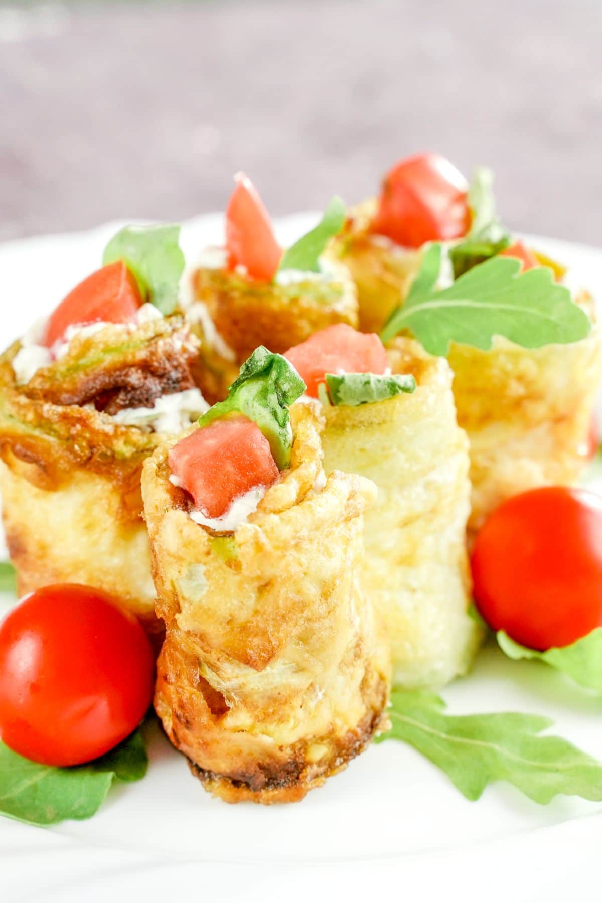 zucchini rolls stuffed with cheese and herbs on white plate