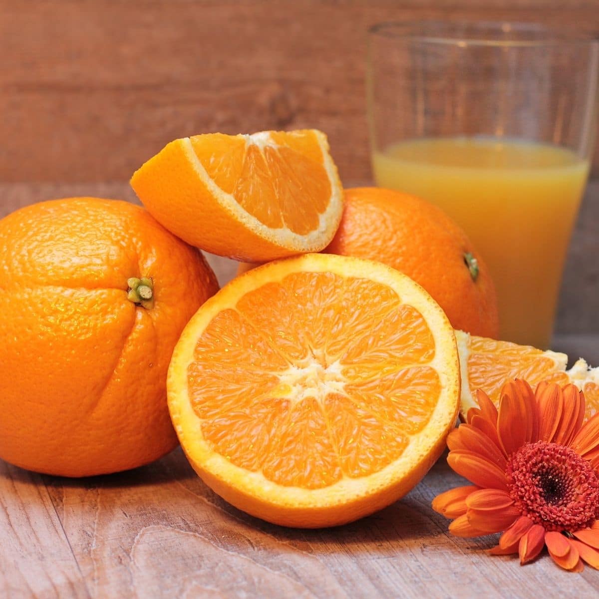 Orange juice and oranges on a table.