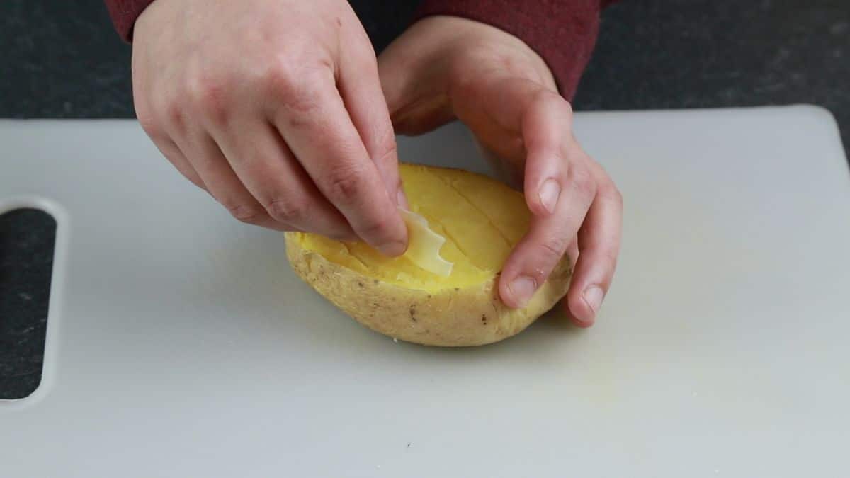 hand putting butter into baked potato
