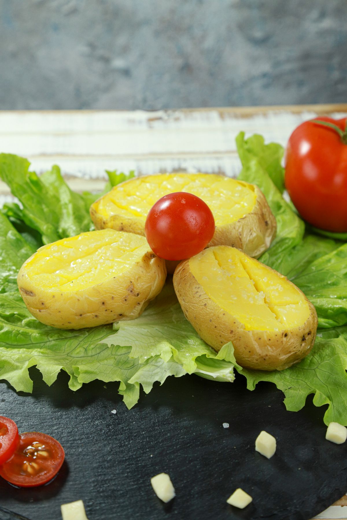 sliced potatoes on black table with lettuce and tomato