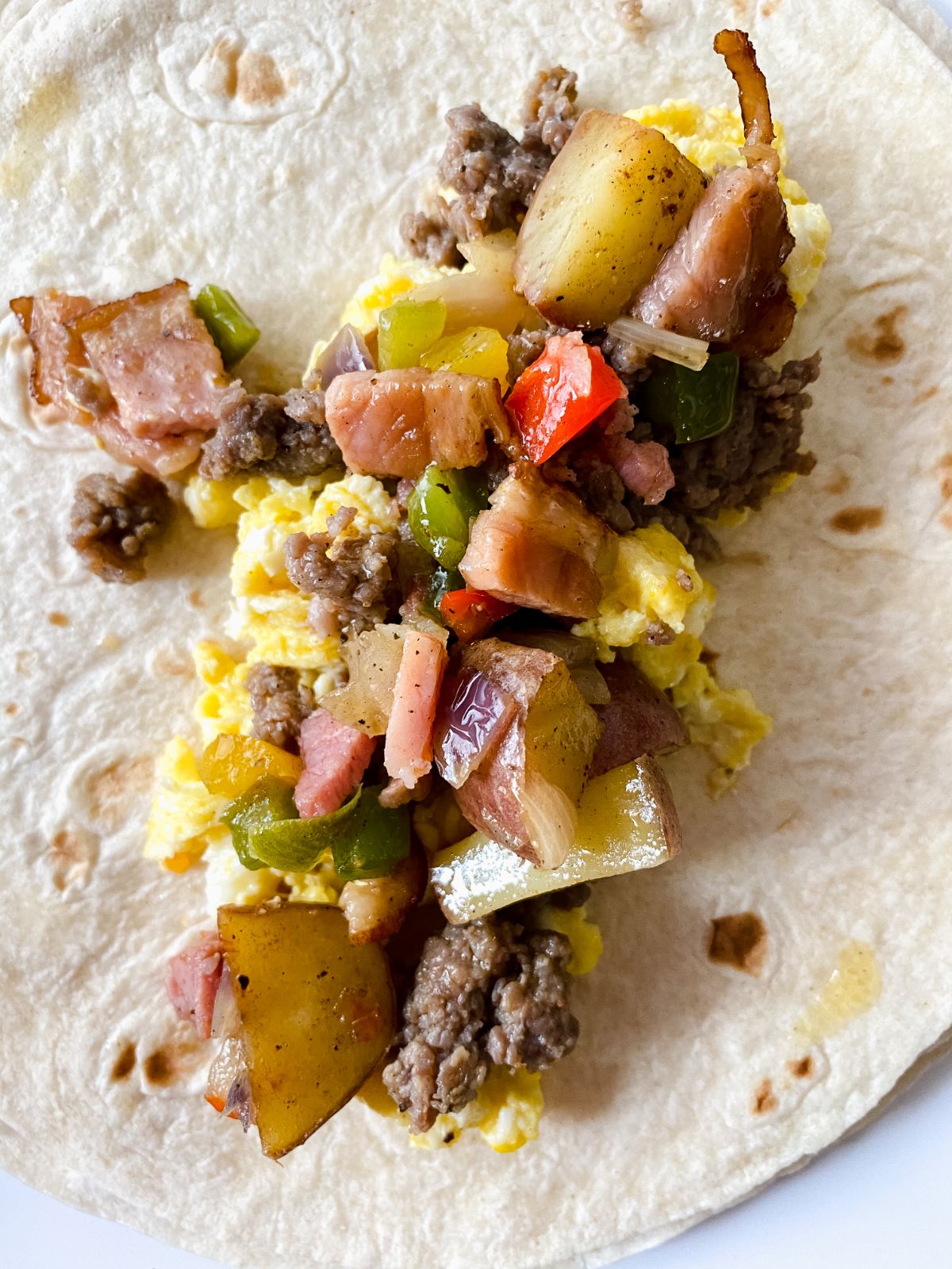 potatoes on top of eggs and sausage on tortilla