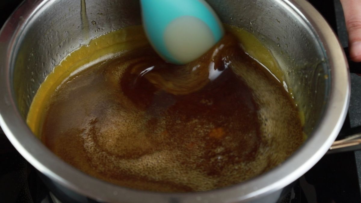 blue spoon stirring sugar liquid in saucepan