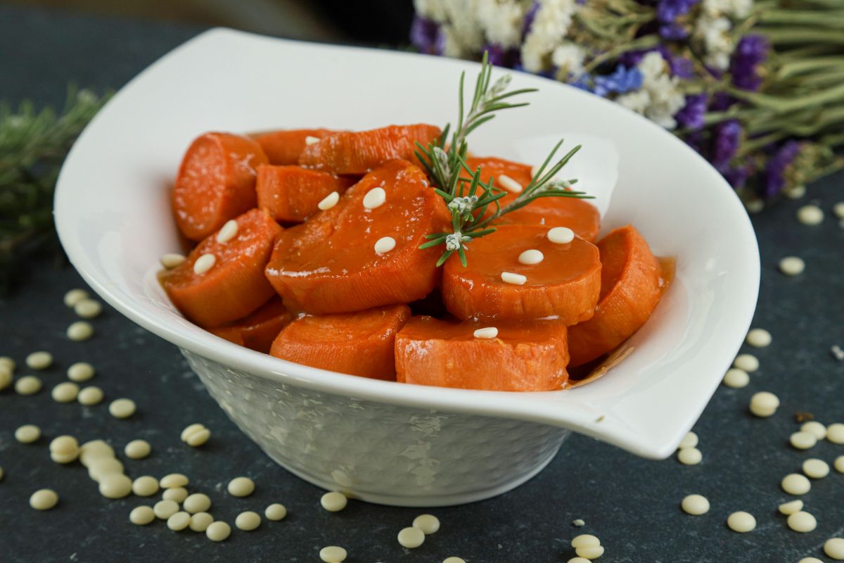 oval white bowl filled with sweet potatoes with herb on top