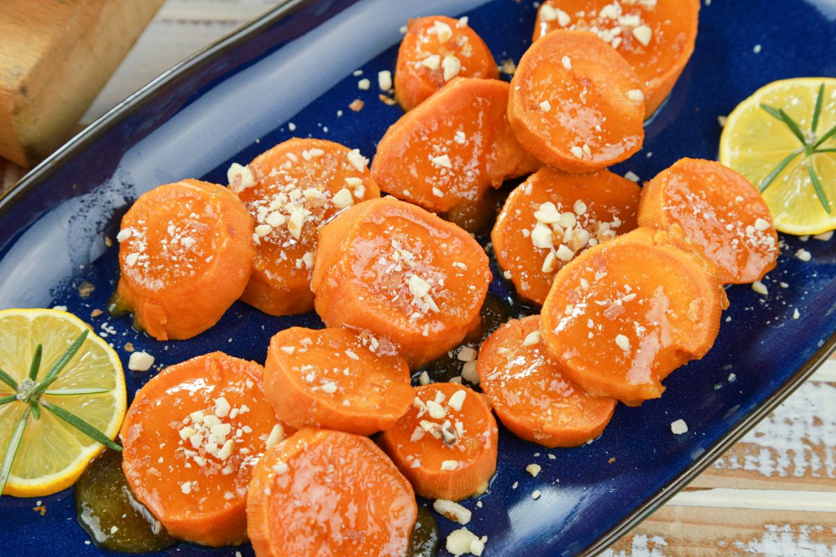 candied sweet potatoes topped with almonds with lime slices on blue plate