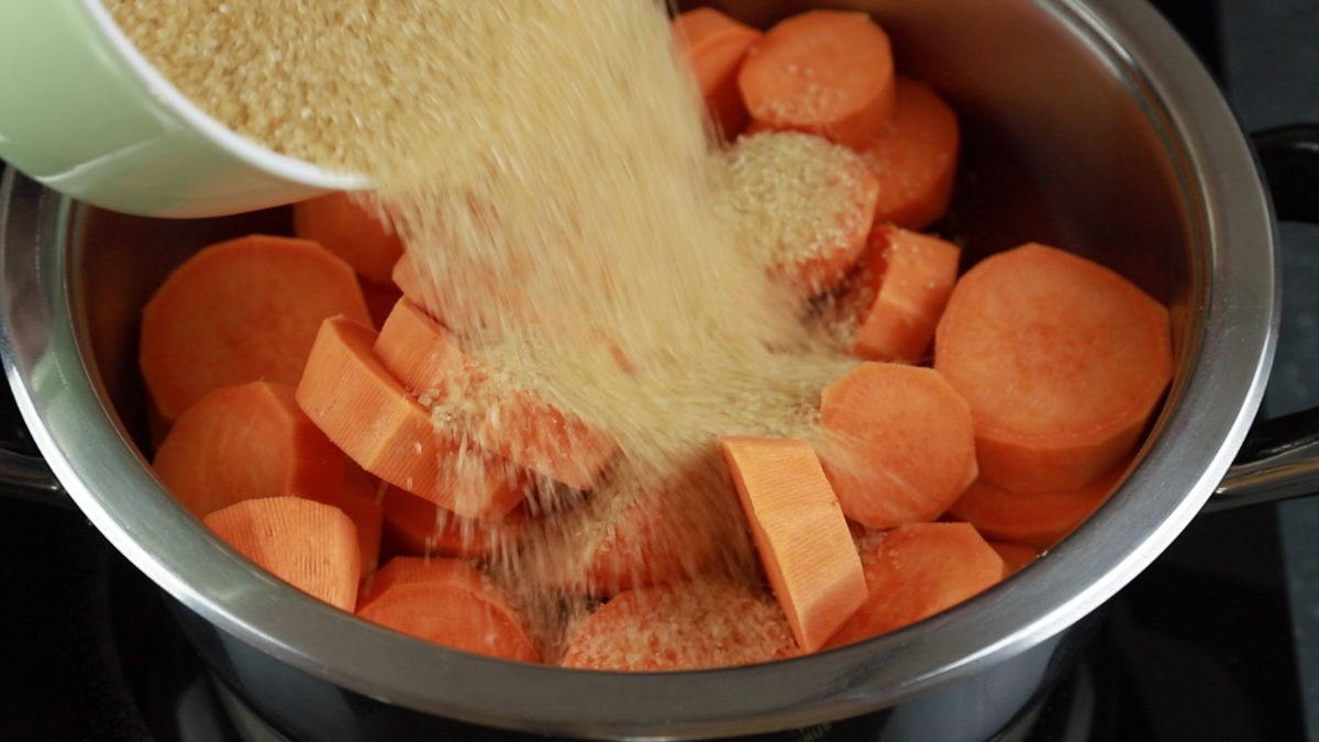 brown sugar being poured over sweet potatoes in saucepan