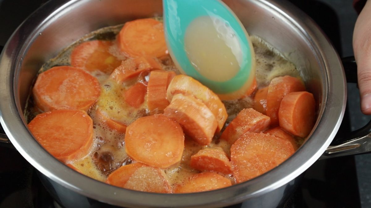 blue spoon stirring sweet potatoes in saucepan