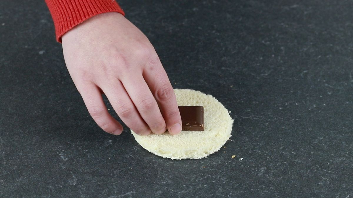 hand putting chocolate on bread round