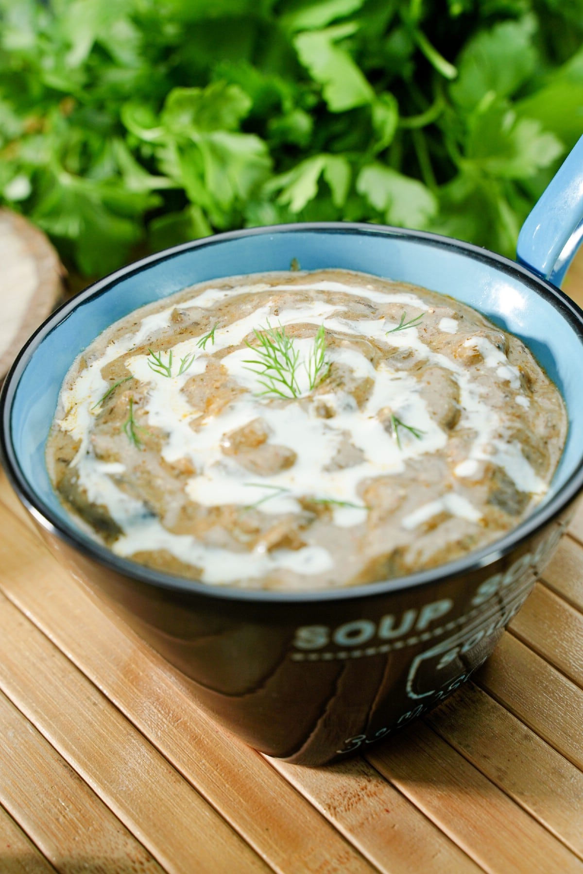 black mug filled with mushroom soup topped with sour cream drizzle