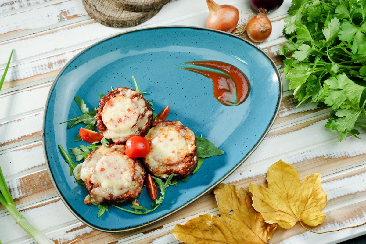 oval teal plate with eggplant pizza bites on wood table
