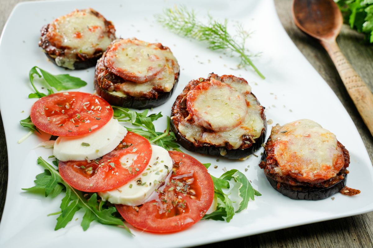 square white plate of pizza bites with caprese salad on side