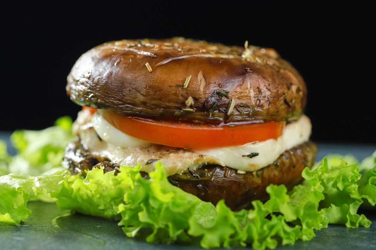 portobello mushroom bun chicken burger sitting on bed of lettuce