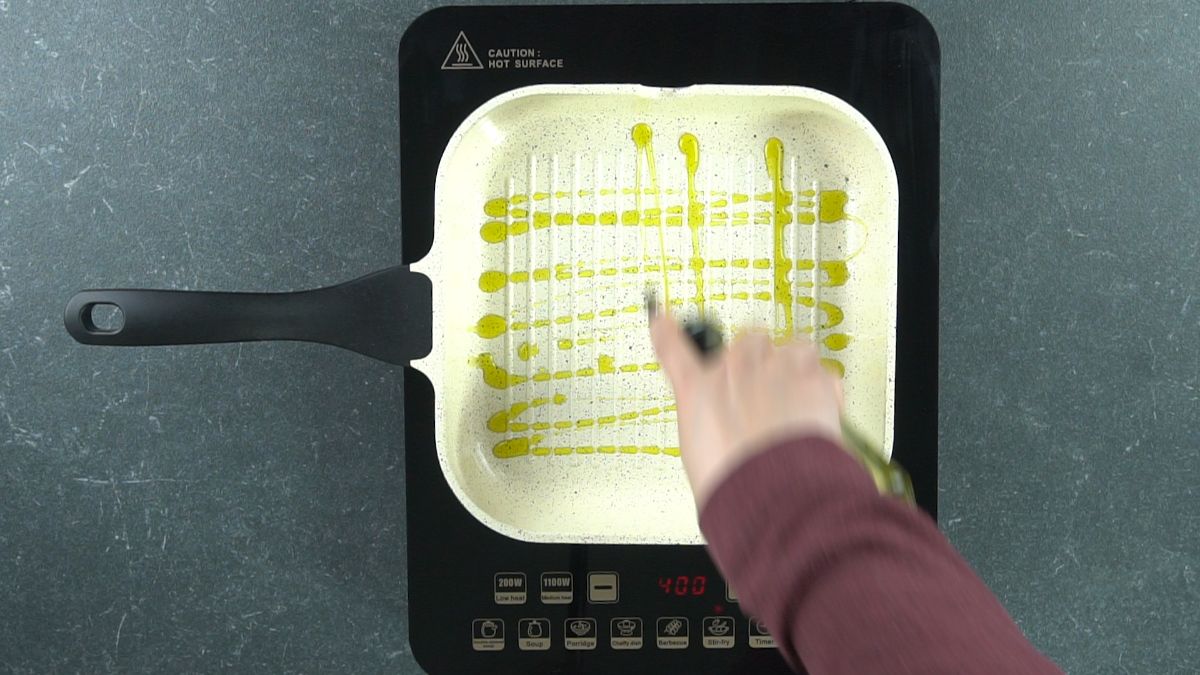 drizzling olive oil in grill pan on hot plate