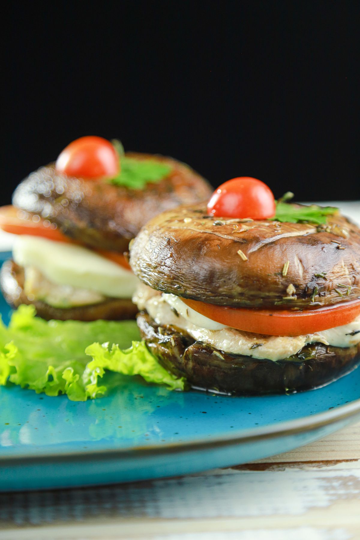 portobello chicken burgers with tomato on blue plate with lettuce